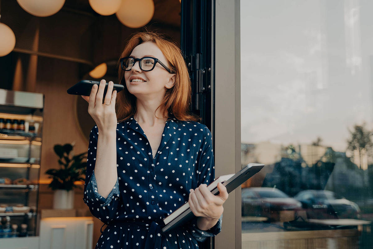 Woman with red hair standing outside a café talking on her mobile phone
